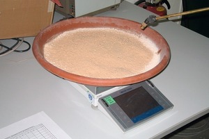  5	Tray containing sample material placed on a scale while spraying water across the sample 